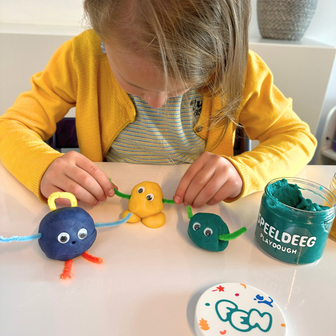 Kind maakt monstertjes met speeldeeg en knutselmaterialen.