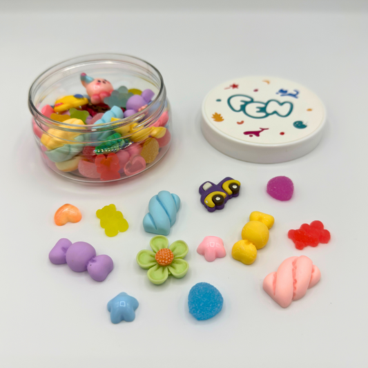 Open potje met kleurrijke fantasiefiguurtjes zoals bloemen, snoepjes en voertuigen voor sensorisch spel