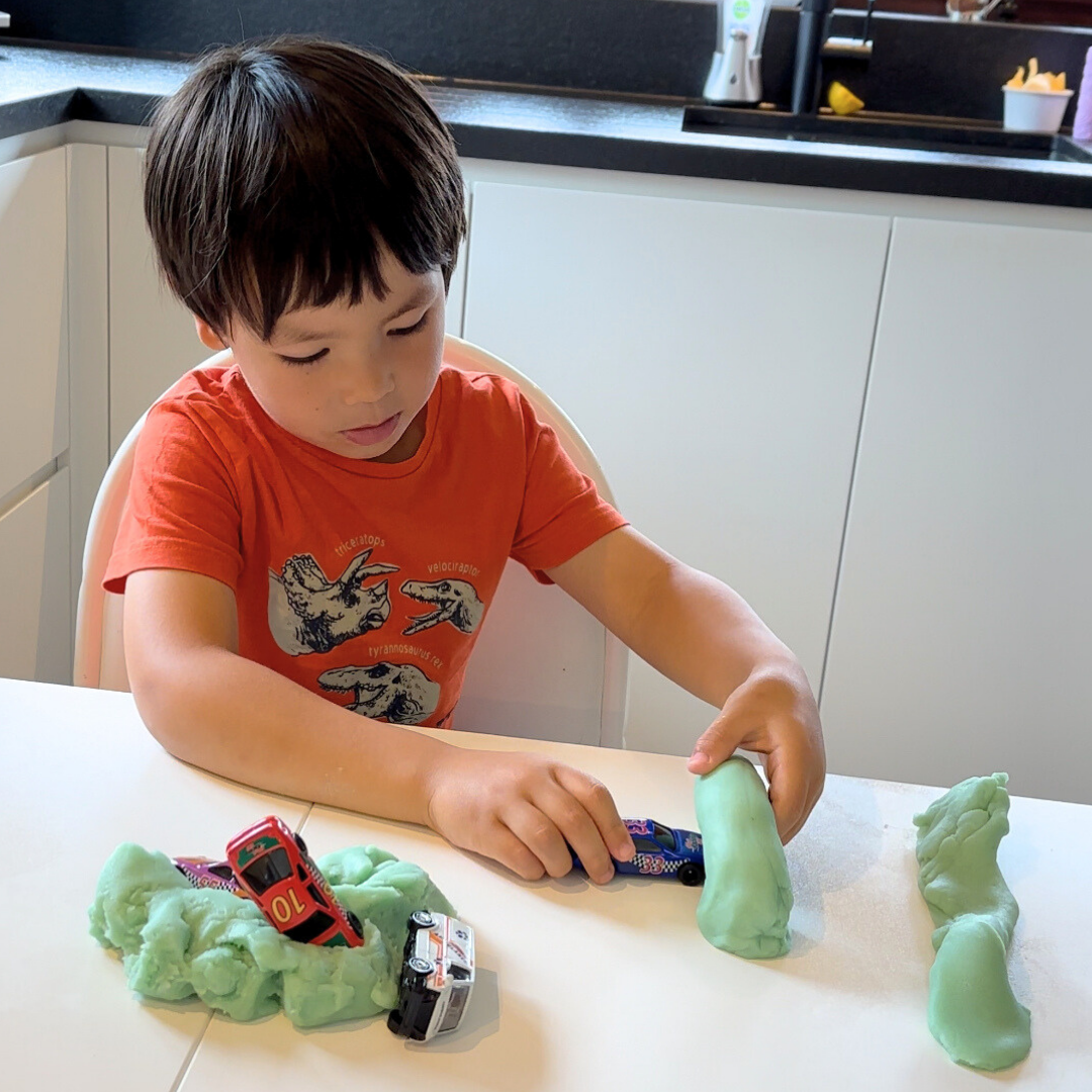 Kind speelt met speelgoed en auto's in speeldeeg