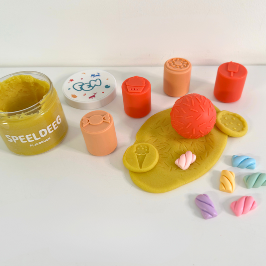 IJs-, snoep- en sprinkle-stempels drukken patronen in geel speeldeeg; marshmallow-figuurtjes erbij