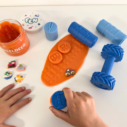 Blauwe verkeersstempels en wiel-roller maken sporen in oranje Fen-speeldeeg