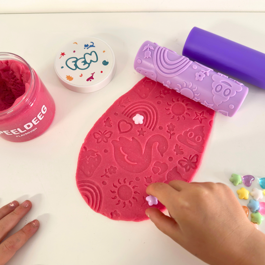 Paarse fantasieroller met zwanen & regenbogen drukt patronen in roze speeldeeg